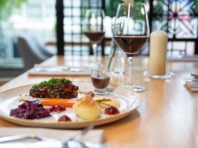 Un tavolo apparecchiato con un pasto elegante, due calici di vino e una candela in un ristorante d'hotel.