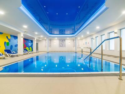Piscina interna moderna con grandi finestre e soffitto a volta blu in hotel.