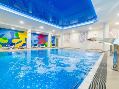 Una piscina interna moderna con pareti colorate e una cascata per il relax.