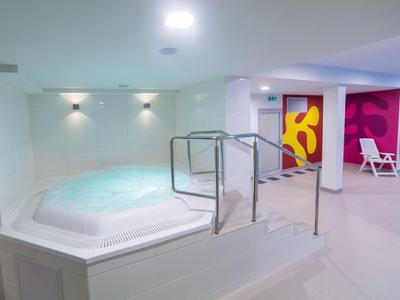 Area jacuzzi moderna con interno luminoso, piastrelle bianche e decorazioni murali colorate.
