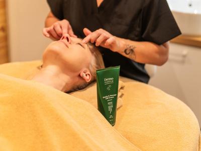 Cliente che riceve un trattamento viso in una spa dell'hotel con crema verde per la pelle.