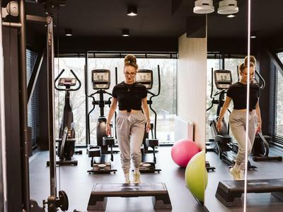 Palestra moderna in hotel con attrezzature cardio e specchi, atmosfera accogliente e luce naturale.