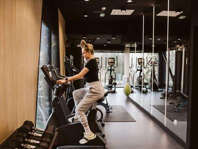 Donna si allena sul tapis roulant in una palestra moderna con specchi e pesi.