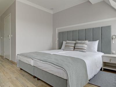 Habitación de hotel moderna con cama doble y esquema de color gris claro.
