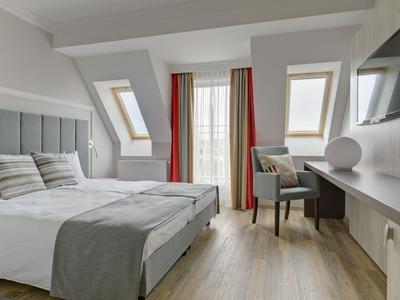Habitación de hotel moderna con cama doble, ventanas tipo tragaluz y escritorio con silla.