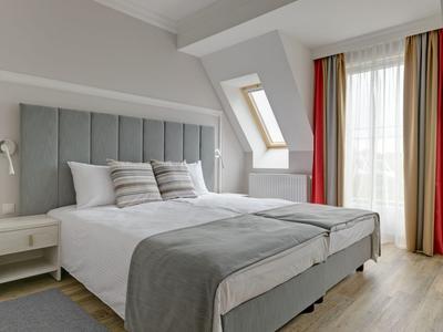 Dormitorio moderno con cama grande, dos mesitas de noche y ventana con cortinas.