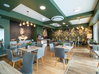 Moderna sala de desayuno con sillas grises, suelo de madera y arte en las paredes en un hotel.