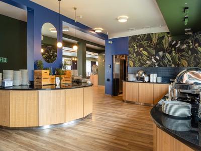 Sala de desayuno moderna con mostradores redondos de madera y mesas preparadas en un hotel.