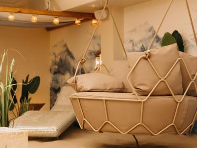 Zona lounge acogedora con sillón colgante, cojines y tonos cálidos tierra.