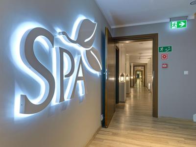 Pasillo moderno de spa con letrero iluminado y suelo de madera en hotel.