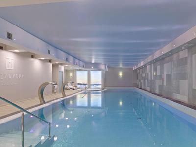Piscina cubierta moderna con agua cristalina y grandes ventanas en un hotel.