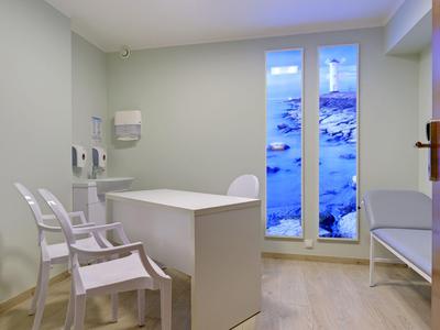 Habitación moderna y luminosa con muebles blancos y grandes ventanas con vista iluminada en azul.