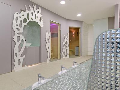 Moderno baño de hotel con marcos de espejo artísticos y accesorios brillantes.