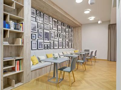Área de desayuno moderna con sillas grises, suelo de madera y fotos en blanco y negro en la pared.