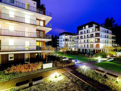Hôtels modernes avec balcons éclairés et jardins bien entretenus la nuit.
