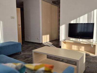 Espace de chambre d'hôtel moderne avec canapé bleu, table basse et télévision écran plat.