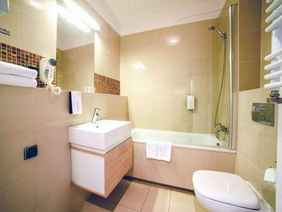 Salle de bain moderne avec baignoire, lavabo et toilettes dans une chambre d'hôtel.