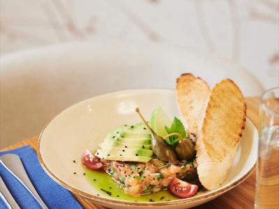 Plat léger avec avocat, tomates, herbes et pain grillé sur une assiette blanche.