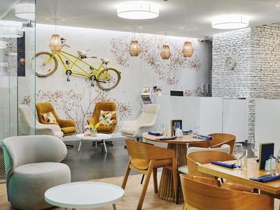 Espace hôtelier moderne avec sièges, lampes suspendues et murs en pierre décoratifs.