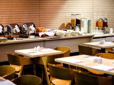 Salon d'hôtel moderne avec buffet de petit-déjeuner et tables dressées en bois chaleureux.