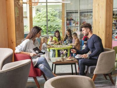 Famiglia che gusta un pasto insieme a un tavolo di legno in un ristorante di hotel moderno.