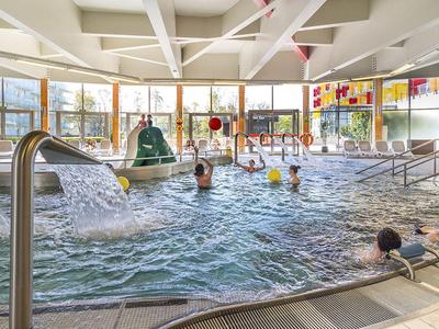 Area interna con grande vasca idromassaggio e giochi d'acqua in un hotel.