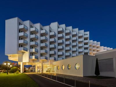 Modernes Hotelgebäude mit markanten Balkonen und klarer Architektur bei Nacht und blauem Himmel.