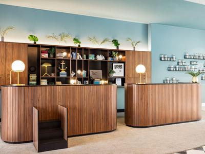 Moderner Hotel-Empfang mit geschwungenen Holztheken und dekorativen Regalen in hellblauem Raum.