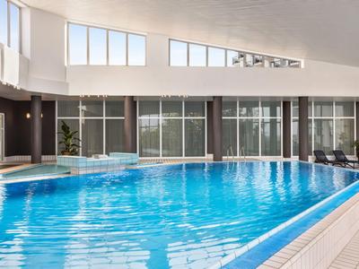 Moderner Innenpool mit klar blauem Wasser und großen Fenstern für Tageslicht.