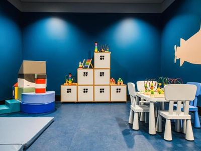 Kinderspielzimmer mit blauen Wänden, Bauklötzen als Schränke und einem weißen Tisch mit Stühlen.