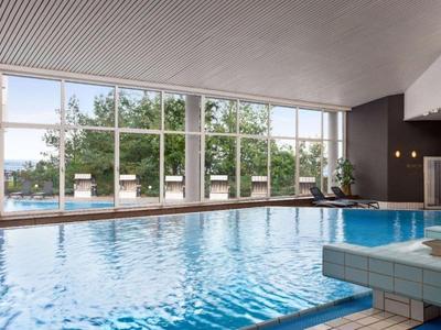 Innenpools mit großen Fenstern und Ausblick auf grüne Bäume, modernes Hotelambiente.