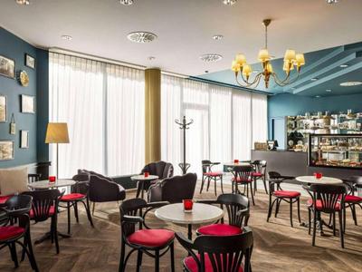 Helles Caféraum mit roten Stühlen, runden Tischen und großen Fenstern für viel Tageslicht.