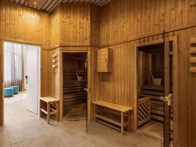 Ein Holzsaunabereich mit zwei offenen Saunatüren und einer Bank in der Mitte.