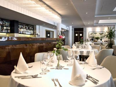 Restaurante elegante con mesas vestidas de blanco, copas y cubiertos para alta cocina.