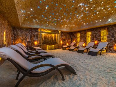 Sala de relajación con sillas reclinables sobre cama de sal bajo techo estrellado.