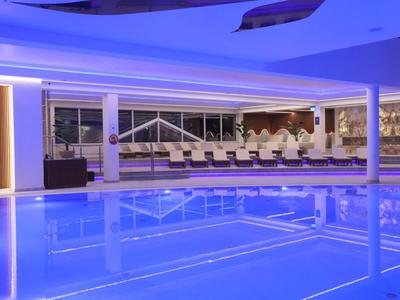 Piscina cubierta moderna con iluminación azul y zona de descanso en un hotel.