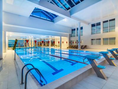 Piscina cubierta moderna con bloques de salida y techo de vidrio en un hotel.