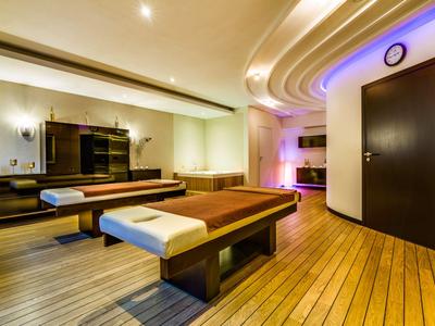 Área de spa moderna con mesa de masaje, suelo de madera e iluminación ambiental.