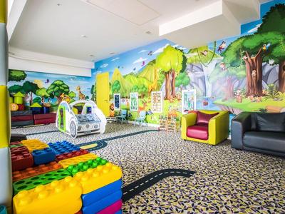 Sala de juegos infantil colorida con asientos y murales en un hotel.