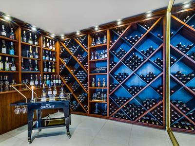 Bodega con muebles de madera, estantes para vino y soporte para botellas sobre suelo claro.