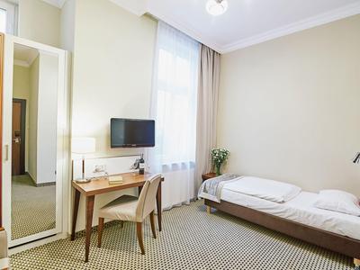 Helles Hotelzimmer mit Einzelbett, Schreibtisch, Stuhl und großem Fenster.
