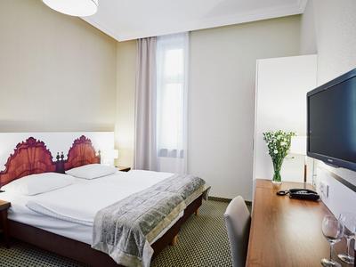 Schlicht eingerichtetes Hotelzimmer mit Doppelbett, Schreibtisch, Flachbildschirm und großem Fenster.