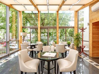 Eleganter Hotel-Loungebereich mit weißen Sesseln und großen Glasfenstern mit Blick ins Grüne.