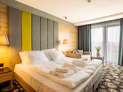 Modern eingerichtetes Hotelzimmer mit Doppelbett, Sitzbereich und Balkon.