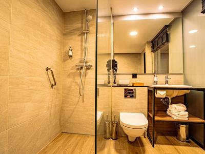 Modernes Badezimmer mit begehbarer Dusche, Toilette und Waschtisch mit Spiegel und Handtüchern.