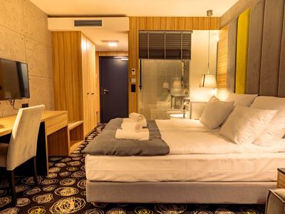 Modern eingerichtetes Hotelzimmer mit Doppelbett, Schreibtisch und Fernseher.