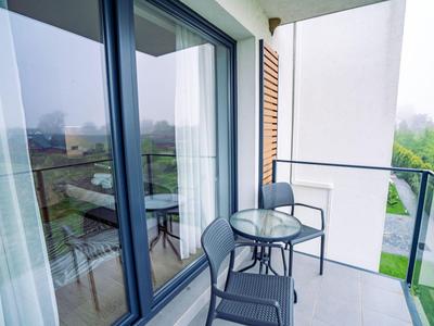 Moderner Balkon mit Glastisch und zwei schwarzen Stühlen an einem Hotelzimmer mit Panoramablick.
