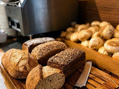 Frisch geschnittenes Brot und Brötchen auf einem Holzbrett in einer Hotelküche.