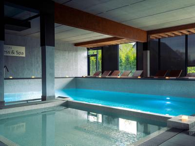 Modernes Hallenbad mit angrenzendem Whirlpool und Sonnenliegen in einem Hotel.