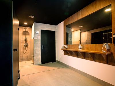 Modernes Hotelbadezimmer mit Holzverkleidung, großem Spiegel und offener Dusche.